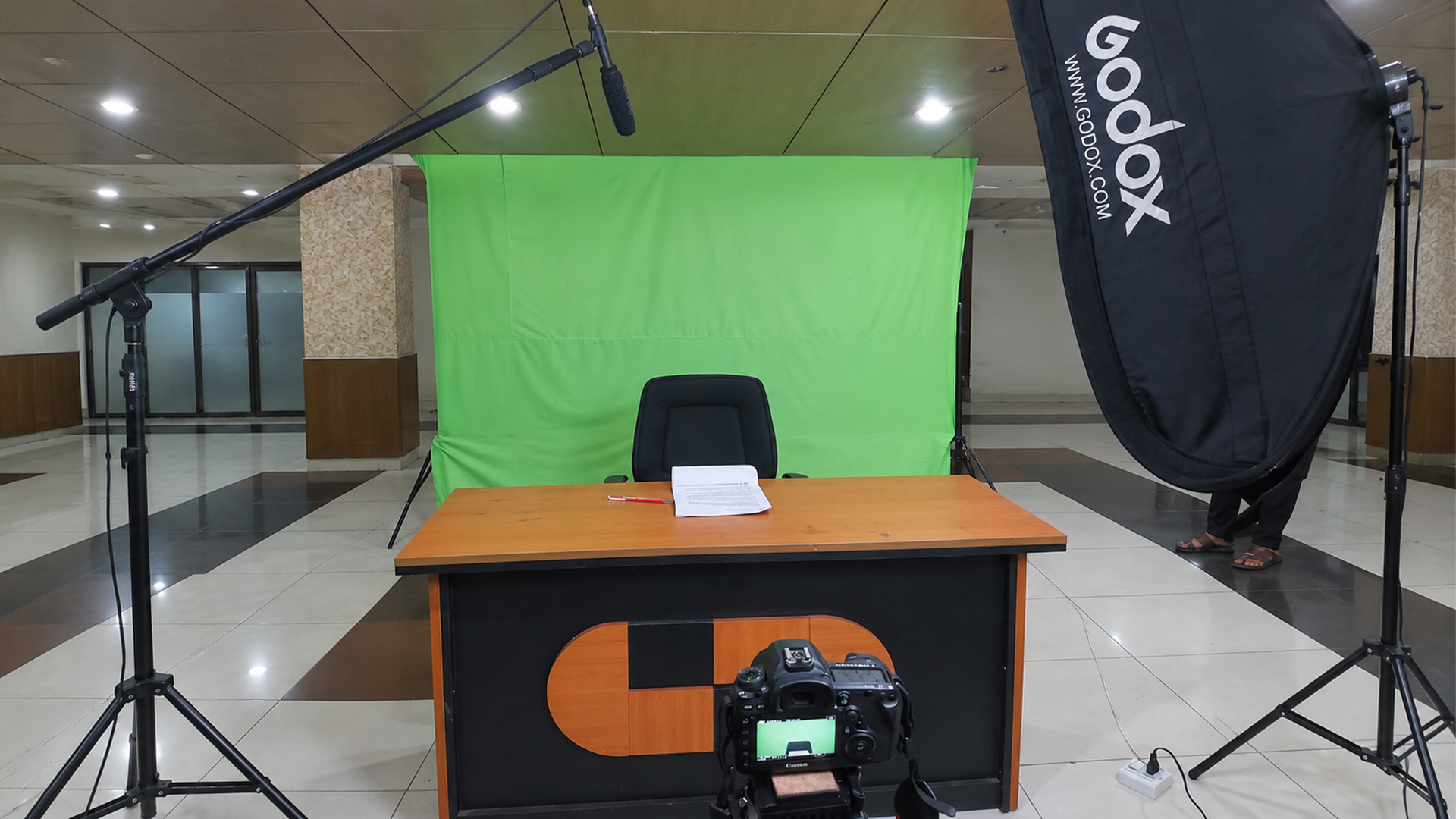 Video production set prepared with a green screen, camera and studio lighting